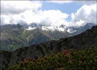 Tatry Wysokie w chmurach, z prawej strony wistowy Szczyt (2382 m), bardziej na lewo wyniose Jaworowe Szczyty (2418 m), oraz niewidoczny przykryty biel potny Lodowy Szczyt (2627 m). Bliej widoczna jest Dolina Biaki.